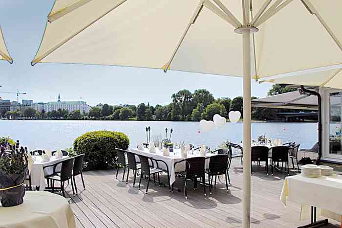 Terrasse mit weiß eingedeckten Tischen direkt an der Alster der Hochzeitslocation Ruder-Club Favorite Hammonia.