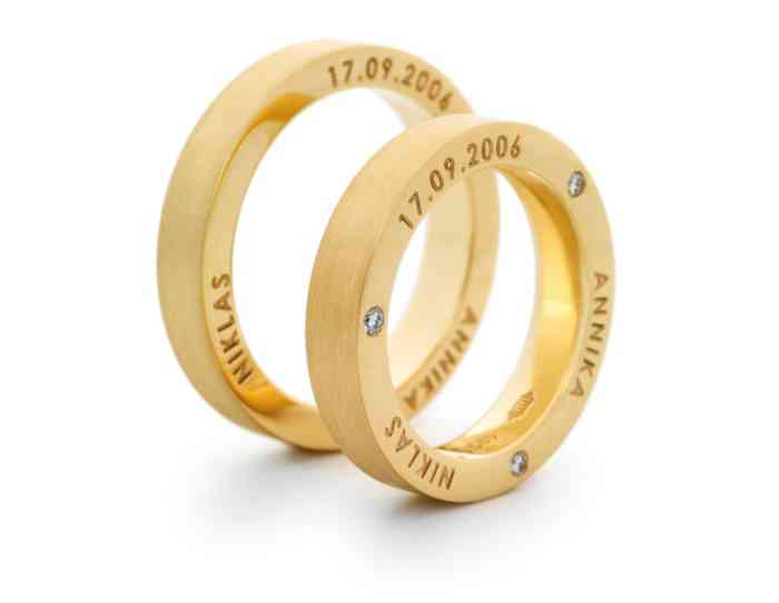 Trauringe aus Gelbgold mit drei Brillanten in der Seitenfläche des Damenrings und den Namen der Eheleute ebenfalls in der Seite der Ringe aus der Goldschmiede Dallmann.