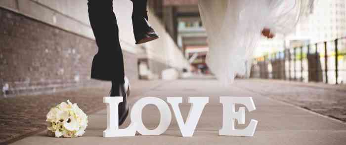 Hochzeitspaar springt über den Schriftzug LOVE.