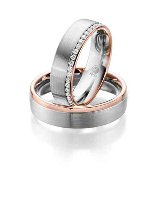 Massive Trauringe mit einem Rosegold-Akzent. Der Ring der Braut ist mit kleinen Diamanten versetzt. 
