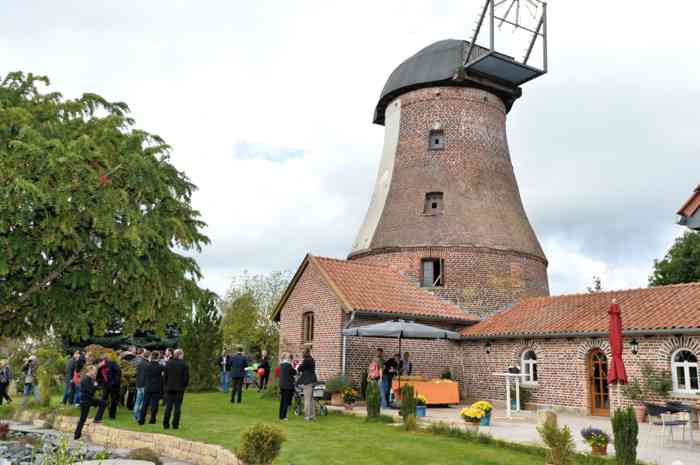 Das Foto zeigt die historische Horster Mühle mit Garten und Hochzeitsgesellschaft. Die Mühle ist Trauort des Standesamtes Garbsen.