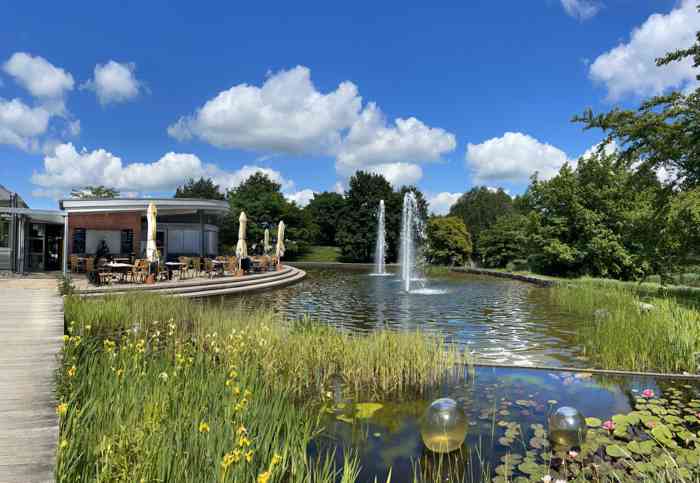 Trauort Pavillon des Standesamt Bad Zwischenahn im Park der Gärten. Im Vordergrund der Parksee mit Fontaine, im Hintergrund der Pavillon mit dem Trauzimmer.