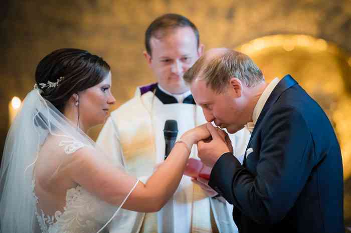 Der Bräutigam gibt der Braut in der Kirche einen Handkuss.