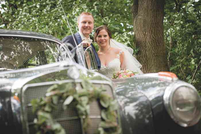 Brautpaar neben Hochzeitsauto Oldtimer Mercedes.